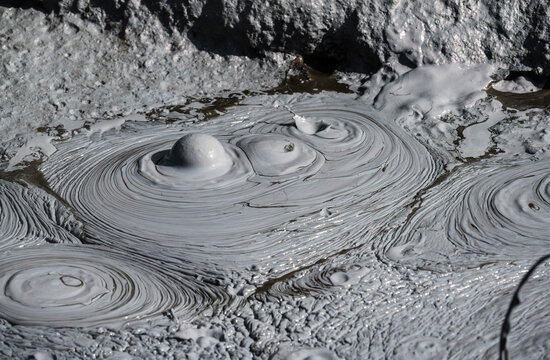 Close up view of grey mud bubbling in a geothermal pool in Iceland.