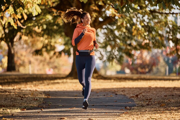 Happy athletic woman jogging on autumn day in nature.