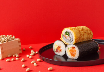 Setsubun, Japanese event..Ehomaki on red background and roasted soy beans called fukumame.  節分。日本の行事。赤背景上の恵方巻と福豆と呼ばれる煎り大豆