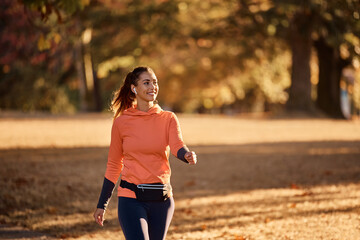 Happy sportswoman enjoys while walking in nature during autumn day.