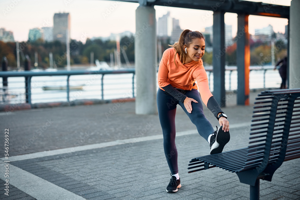 Poster Happy female athlete stretching while working out outdoors.