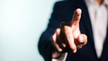 Businessman in suit point finger at camera in front of white background.