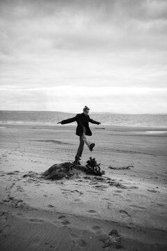 Young woman holding balance on a wooden stump at the beach