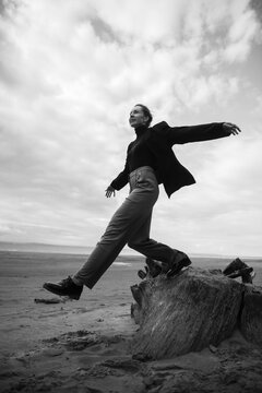 Young woman balancing on a wood stump at the beach