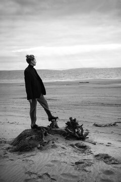 Young woman standing on a wood stump at the beach