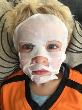 funny portrait of young boy with beauty mask on his face