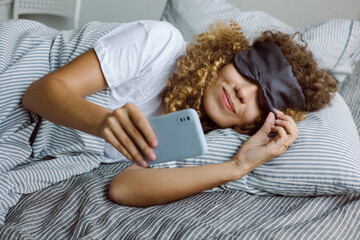 Young woman woke up early in the morning and looks at the phone
