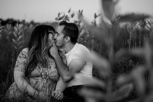 Black and white image of couple kissing in field