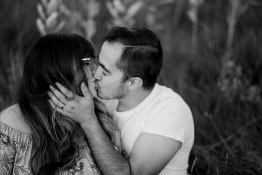 Black and white image of couple kissing in field