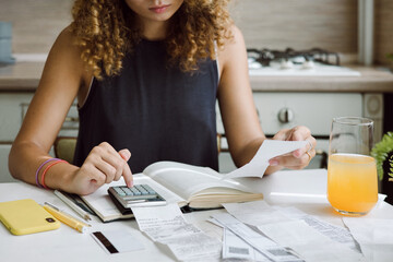 Young woman counting bills for payment on a calculator