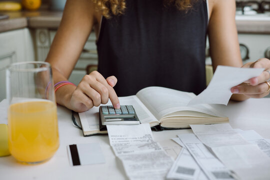 Young woman counting bills for payment on a calculator