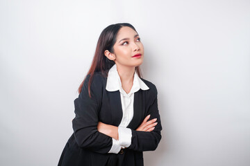 Fototapeta premium Portrait of a confident smiling Asian girl boss wearing black suit standing with arms folded and looking at the camera isolated over white background