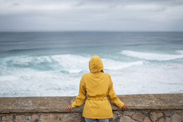 young woman with raincoat by the sea