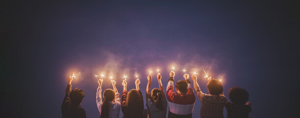 Group of young friends enjoy with burning sparkler in hands together