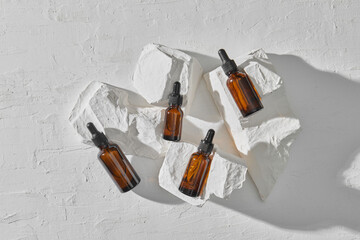 Serum in glass bottles with dropper lid on stand made of white stone. 
