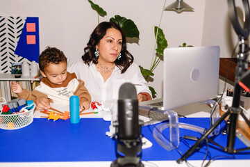 Blogger mom working while her toddler plays at office desk