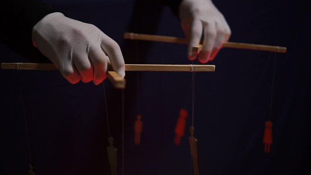 The hands of an anonymous puppeteer manipulate human puppets. The concept of globalization of the planet