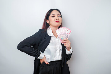 A portrait if a young businesswoman with a stack of money in Indonesian Rupiah in her hands...