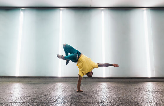 Young man doing one handed handstand and breakdancing