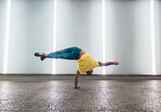Young man doing one handed handstand and breakdancing