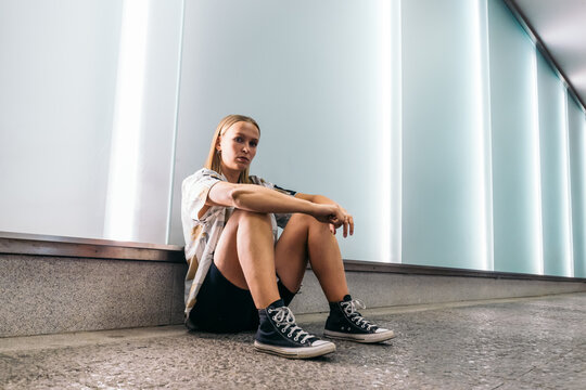 Stylish young woman sitting on the floor in the city