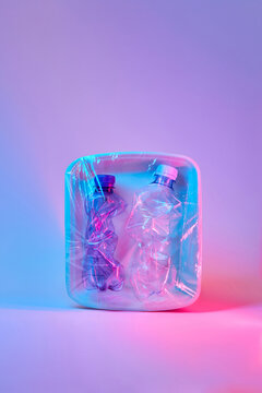 Used plastic bottles on neon purple background.