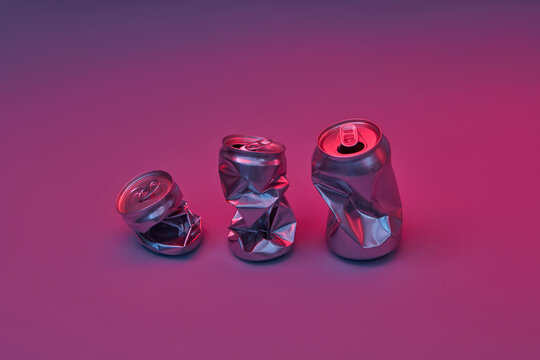 Crushed aluminum cans on neon purple background.