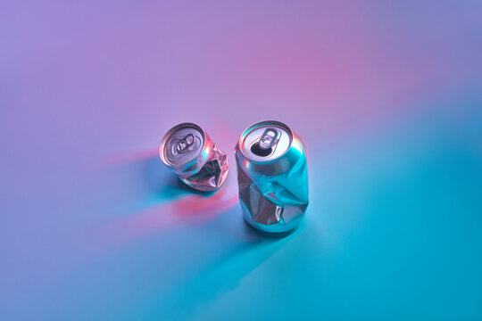 Crumbled tin cans on toned neon blue background.