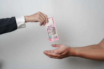 A portrait of businessman giving money in Indonesian Rupiah for business deal or payment or charity