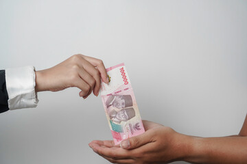 A portrait of businessman giving money in Indonesian Rupiah for business deal or payment or charity