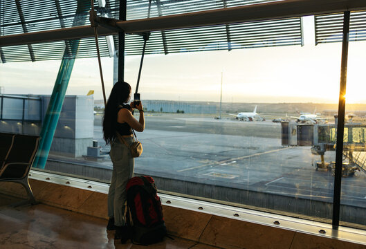 Woman at the airport taking photos of the sunrise while waiting