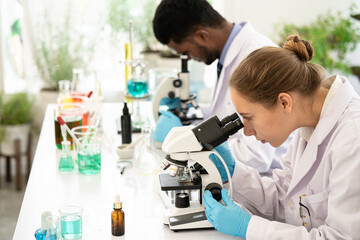 Fototapeta premium Group of Microbiologist Looking at a Lab-Grown Cultured Vegan Meat Sample in a Microscope. Medical Scientist Working on Plant-Based. medical biotechnology research laboratory using microscope.