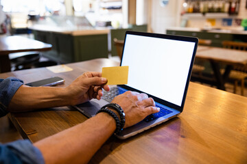 Crop man using laptop and credit card in cafe
