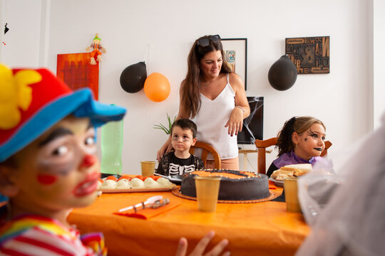 Children In Halloween Outfirs At Party Table