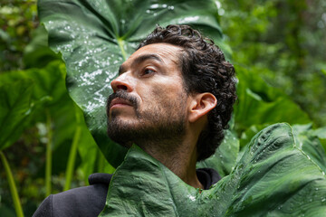 A profile portrait of a man surrounded by plants