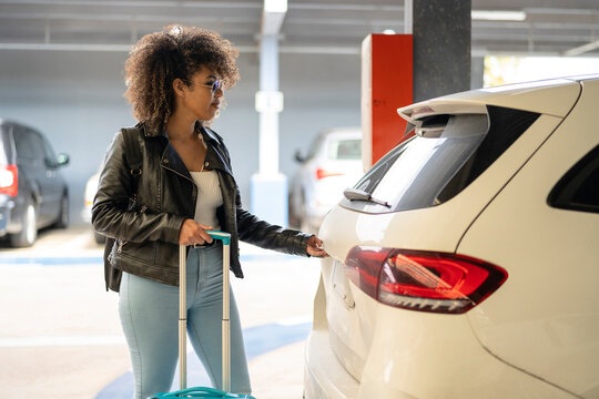 Black traveler opening car trunk
