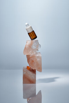 A cosmetic bottle with a pipette balances on stacked of salt