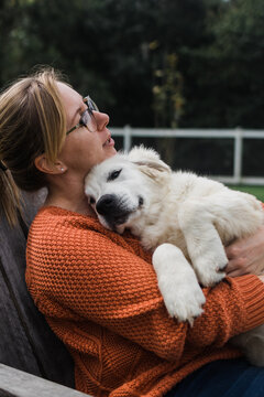 Woman Cuddling Golden Retriever Puppy