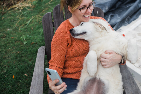 woman holds a wriggly puppy as she takes a selfie