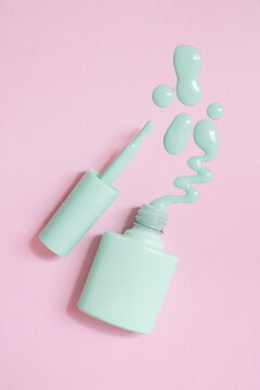 pastel green nail polish spill on pink background