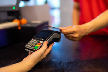 Customer making wireless or contactless payment using credit card. Cashier accepting payment over nfc technology.