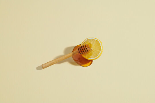 Honey dripping wooden honey dipper on the lemon slice