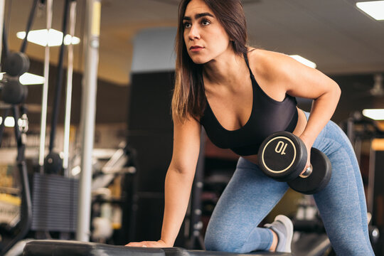 Strong woman training rowing in the gym