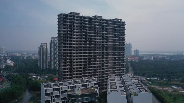Aerial orbit of facade of abandoned concrete shell of residential high-rise real estate and construction development