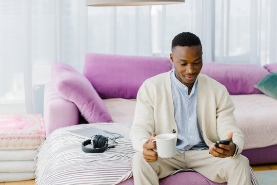 A man with a phone and a cup of tea