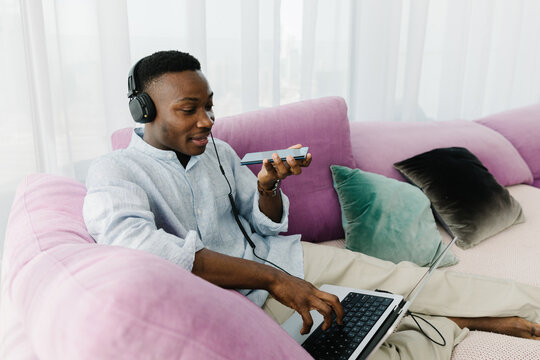 A man making an audio message on the phone on the couch