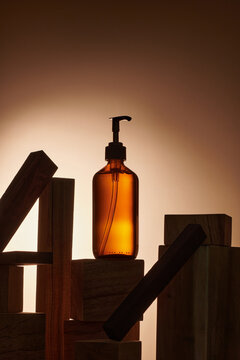 Dark amber glass pump bottle on wooden cut podium  with back light