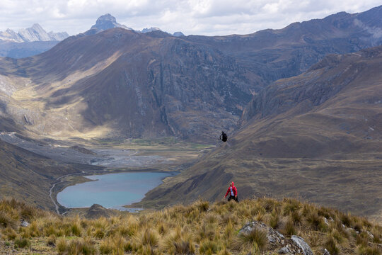 Hombre tirando hacia arriba su mochila, en una meseta o p&aacute;ramo, cerca a una laguna y una monta&ntilde;a con el cielo nublado, en los Andes Per&uacute; Sudam&eacute;rica