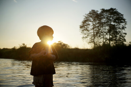 Cute little Asian boy in the creek at sunset