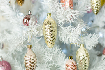 Christmas decorations on a white Christmas tree. A set of vintage glass pink and silver cones.